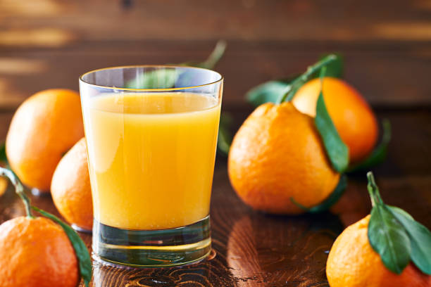 bicchiere fresco di succo d'arancia sul piano del tavolo rustico - leaf cup breakfast drink foto e immagini stock