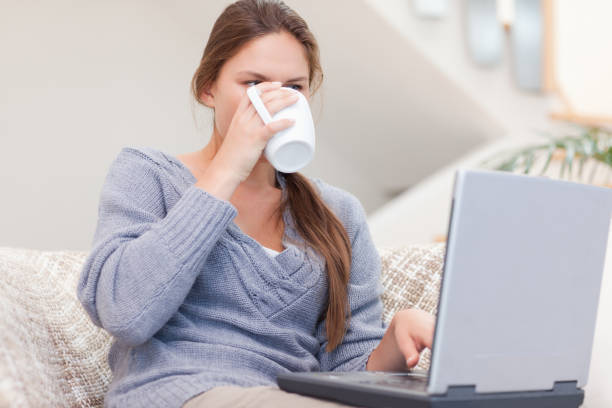 istock Woman using a laptop while drinking a cup of a tea 825882972