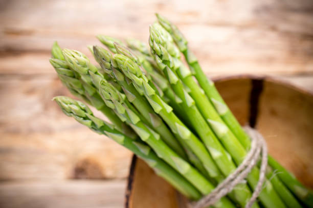 istock Asparagus on the wooden background. 825891198