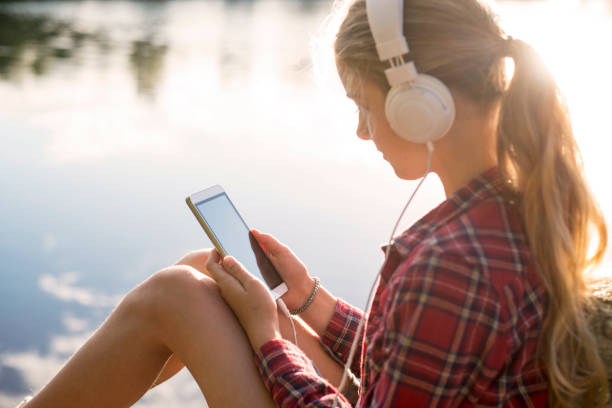 istock Girl sitting at the lake using her smartphone 825895204