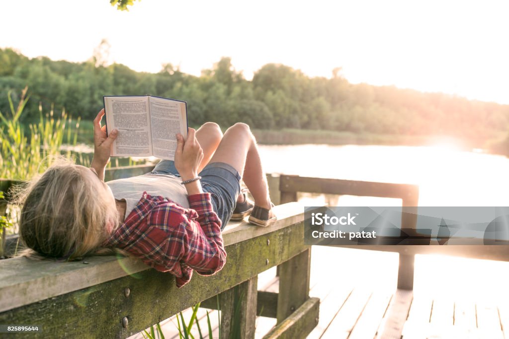 Niña leyendo un libro en el lago - Foto de stock de Leer libre de derechos