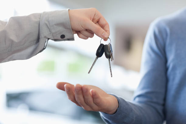 Man giving keys to someone Man giving keys to someone in a car shop wavebreakmedia stock pictures, royalty-free photos & images