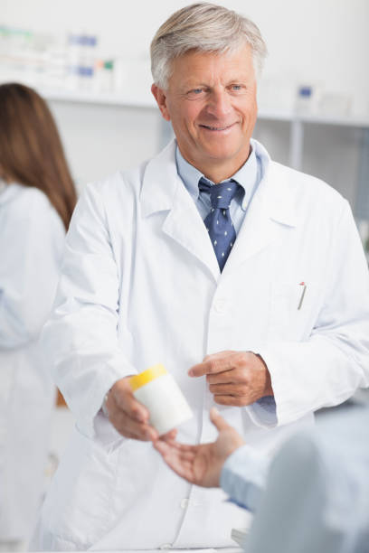 istock Pharmacist holding a box of pills while pointing at it 825911328