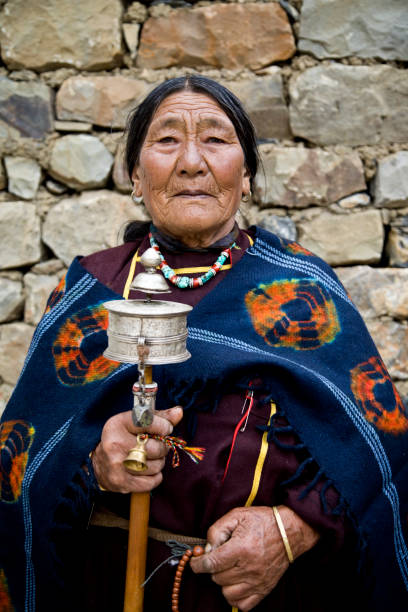 istock Old woman holding hand prayer wheel 825911428