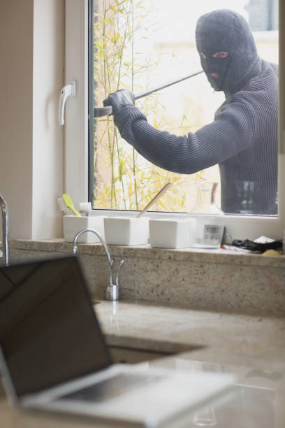 istock Burglar opening window with crow bar 825911486
