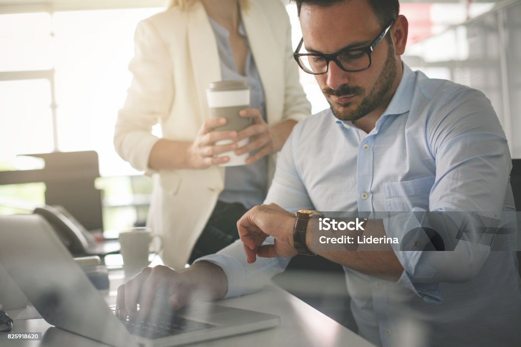 Gente de negocios trabajando en oficina. Hombre de negocios mirando al reloj una espera algo. - Foto de stock de Reloj libre de derechos