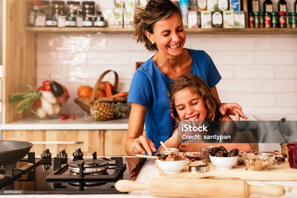 Bambina che cucina con sua madre in cucina. - Foto stock royalty-free di Cucinare