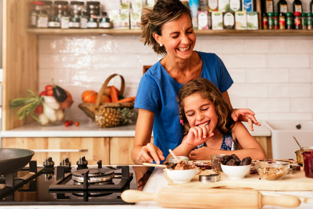 маленькая девочка готовит с матерью на кухне. - bakery baked biscuit sweet food стоковые фото и изображения