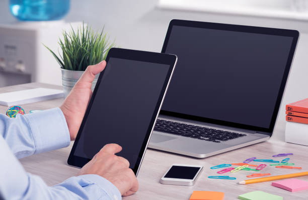 Businessman holding and working with digital tablet pc. Modern office desk workplace with laptop computer mockup and tablet pc mockup in Businessman hands.