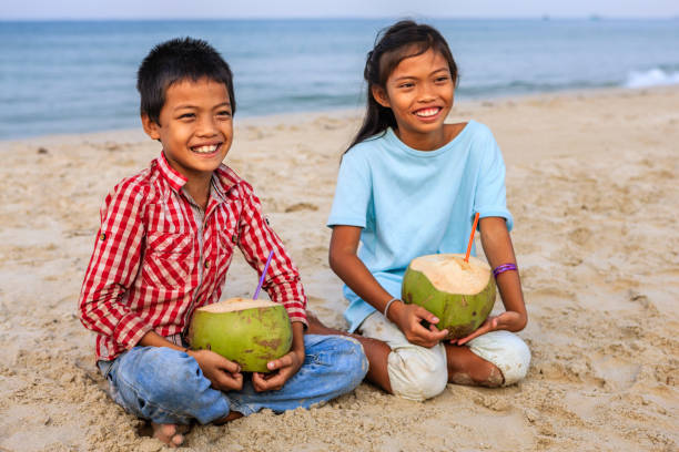 istock Cambodian children holding coconuts on the beach, Cambodia 825934332