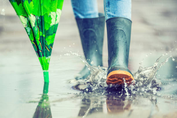 Girl in rubber boots outdoors in rainy day.