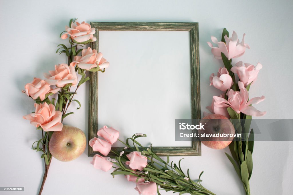 Wooden photo frame, apple and pink roses on watercolor paper. Flat lay table with gentle floral ornament. Wedding background. Pastel flowers on white backdrop. Horizontal composition with text place Anniversary Stock Photo