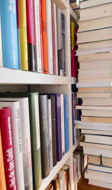 istock Filled books shelf close up with a stack of books leaning at it 825944026