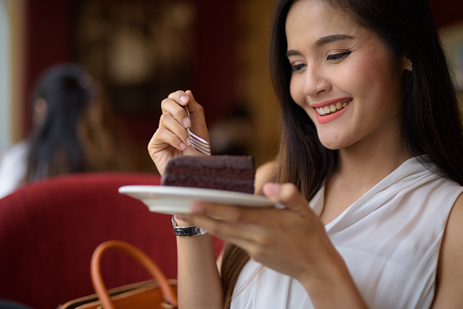 Portrait of young beautiful Asian businesswoman relaxing at the coffee shop in Bangkok Thailand horizontal shot