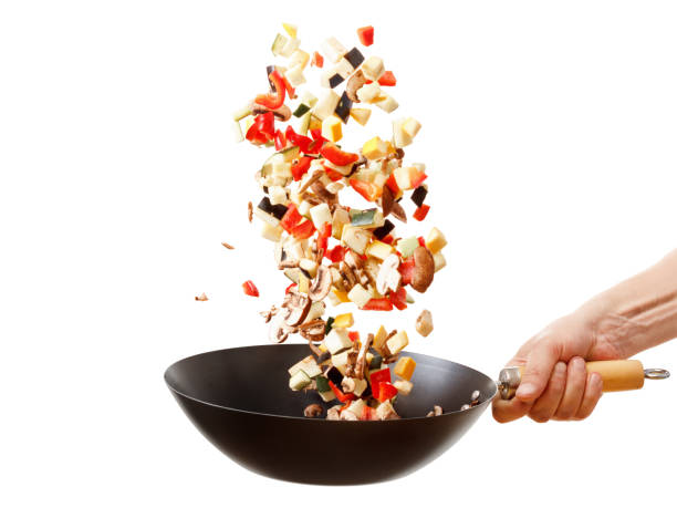 istock Fresh vegetables flying into a pan, isolated on white background 825958054