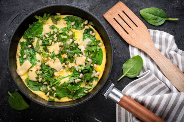 istock Spinach tortilla in pan on dark background. Omelet with eggs, spinach, pine nuts and vegetables. Delicious breakfast or appetizer snack. Top view 825961348