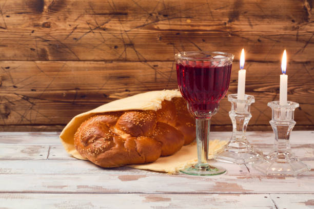 concept de shabbat avec vin verre et challah du pain sur la table en bois - challah jewish sabbath photography candle photos et images de collection