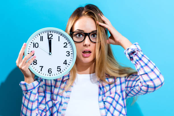 istock Woman holding clock showing nearly 12 825972252