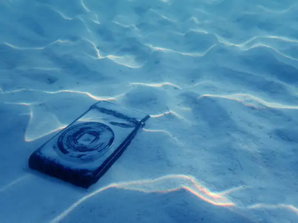 Photo of Compact camera on the sand under sea water