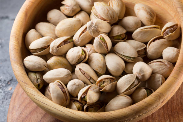 istock pistachios in wooden plate 825973722
