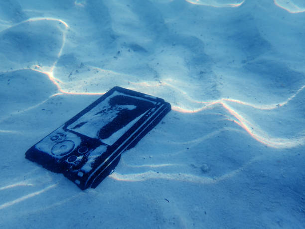 cámara compacta en la arena bajo el agua de mar - dropped call fotografías e imágenes de stock