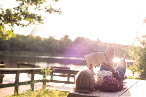 istock Girl reading a book at the lake 825985396