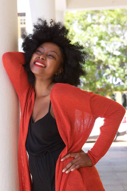 istock attractive smiling african woman leaning on wall 825993122