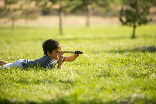 маленький мальчик, держащий бинокль в парке - little boys discovery binoculars child стоковые фото и изображения