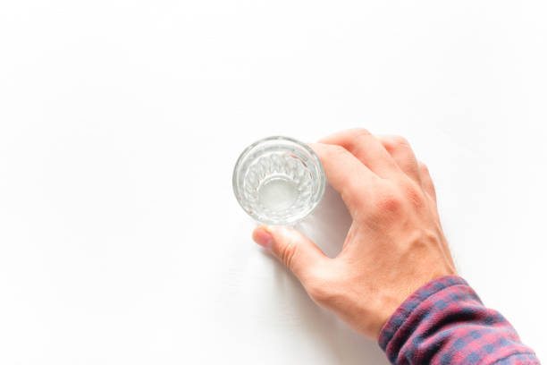 istock Man holding a glass of vodka on a white background 826002766