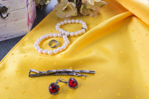 браслеты и серьги и кольцо на желтом фоне - blur band стоковые фото и изображения