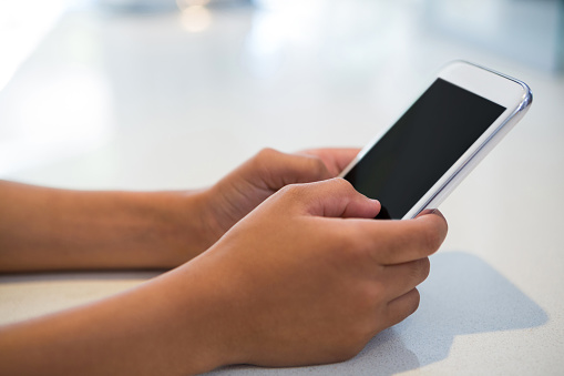 Close-up of girl using mobile phone at kitchen counter