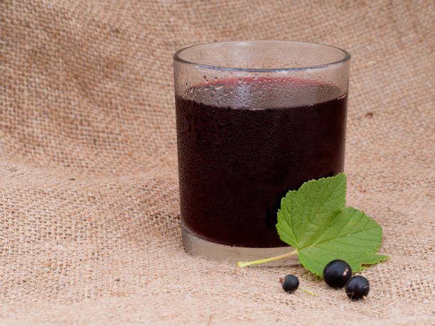 istock Blackcurrant juice in glass. Hessian behind. 826015228