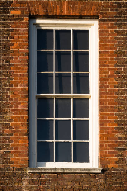 istock Close-up of white window in red Tudor building brick wall 826018334