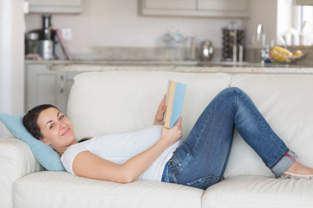 istock Pregnant woman reading on couch 826025608