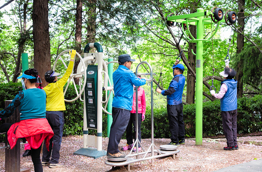 Busan South Korea seniors exercising in park using modern machines.