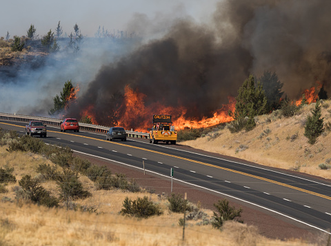 This image shows a wildfire raging through brush and trees near Highway 97, north of Madras, Oregon on 7/25/2017. Vehicle traffic was allowed to continue on the highway.