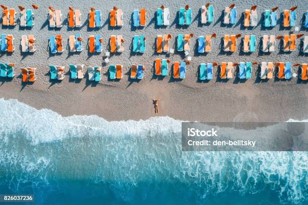 Beautiful Young Woman On The Sea At Sunrise In Oludeniz Turkey Aerial View Of Lying Woman On The Beach With Colorful Chaiselounges Top View From Drone Seascape With Girl Azure Water And Waves Stock Photo - Download Image Now