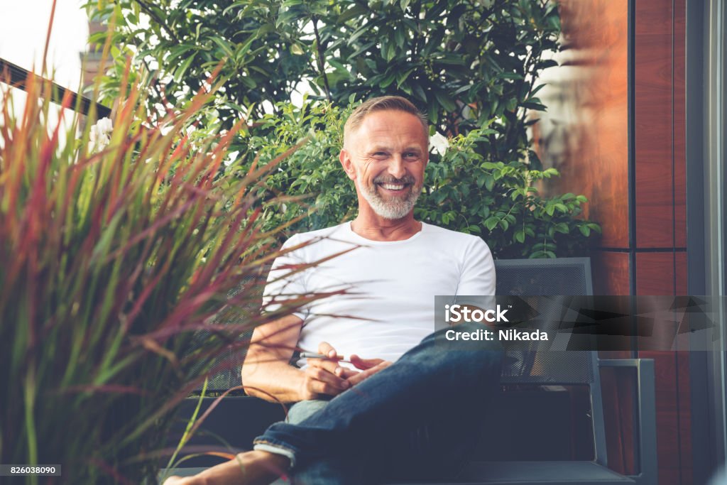 Homme barbu assis sur un balcon - Photo de Hommes libre de droits