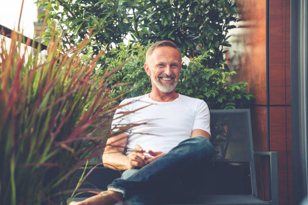 bearded man sitting on a balcony - businessman one man only standing elegance imagens e fotografias de stock