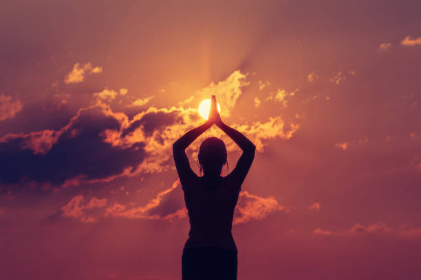 Young woman practicing yoga at sunset on the shore of a lake or river