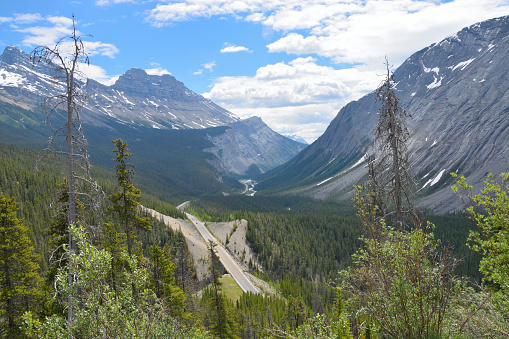 Trans-Canada highway stretches through burly mountains, here, it is nestled inbetween mountains near Jasper National Park, British Columbia, Canada.