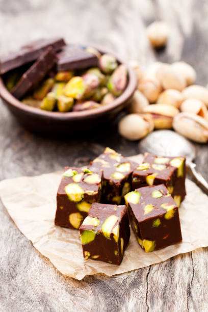 istock Dark  chocolate cubes with pistachios on wooden background 826055422