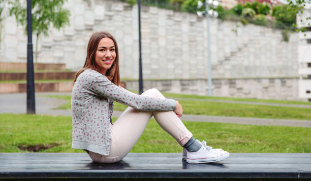 istock Beautiful young woman sitting on park bench 826058298