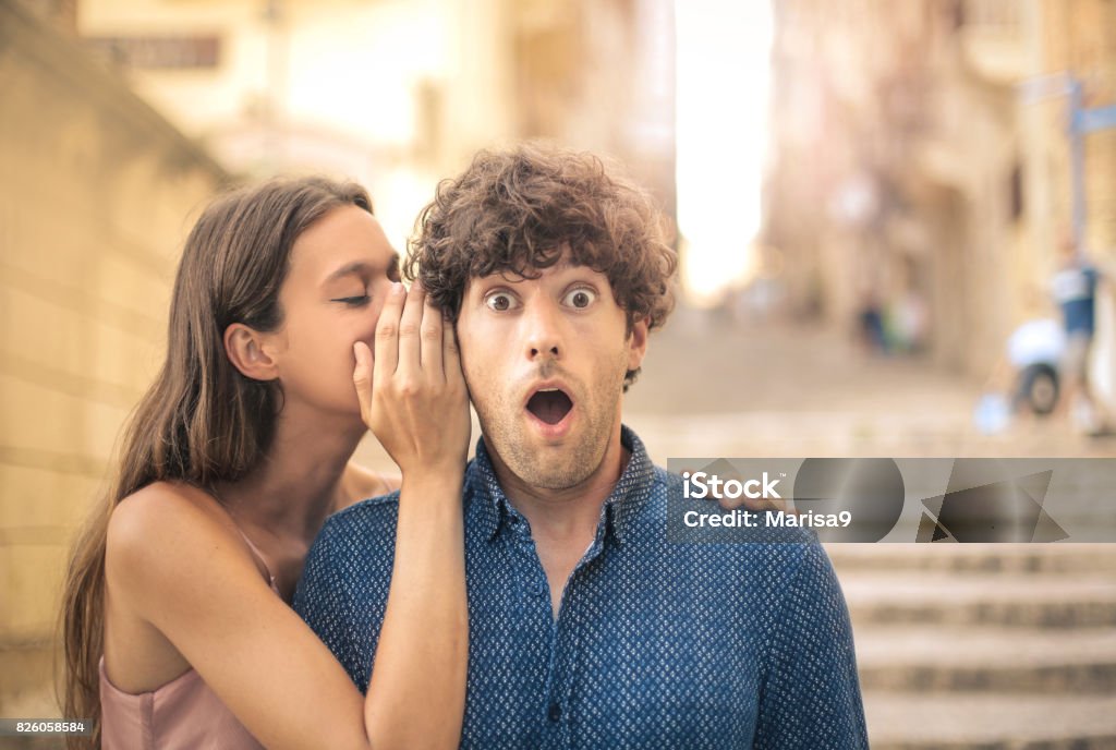 Whispering a secret Beautiful young woman whispering a secret into her boyfriend's ear Whispering Stock Photo