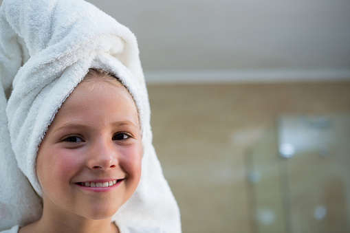 Portrait of smiling girl with hair wrapped in towel in bathroom