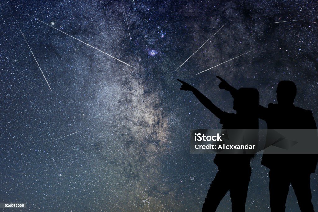 Silhouette of young couple watching Meteor Shower. Nigh Sky. Perseids Stock Photo