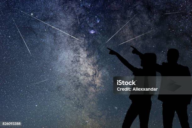 Silhouette Of Young Couple Watching Meteor Shower Nigh Sky Stock Photo - Download Image Now