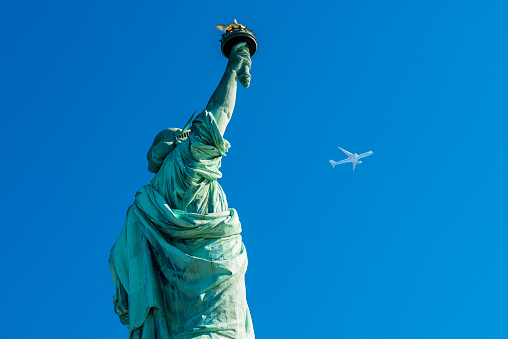 Rear view of Statue Of Liberty with an airplane in Liberty Island, New York City, NY, USA. Horizontal composition. Image taken with Nikon D800 and developed from Raw format.