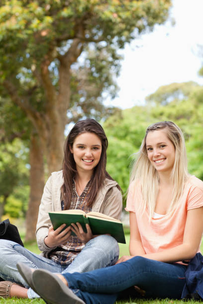 istock Cute teenagers sitting while studying with a textbook 826105060