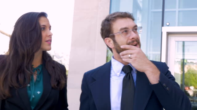 A businessman walking and talking with his businesswoman colleague outside